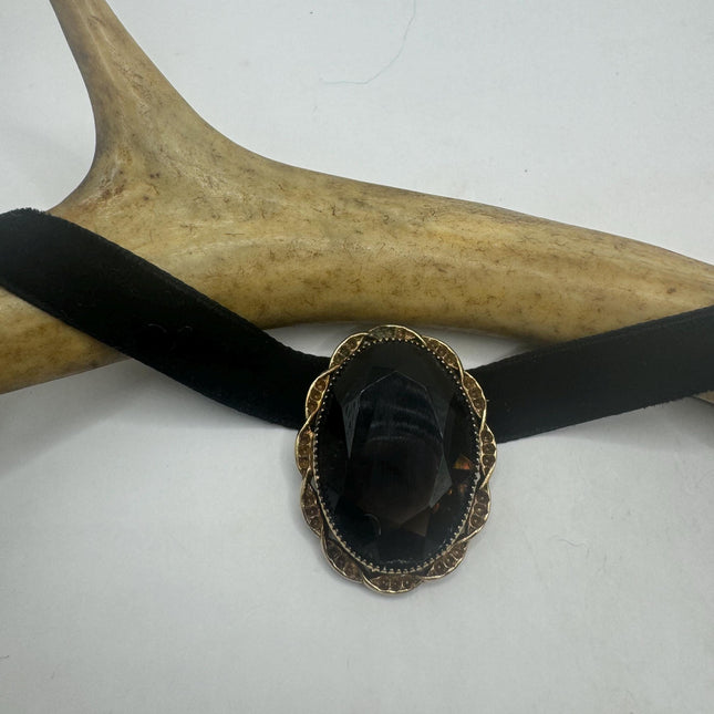 large smoky topaz stone framed in delicate gold setting about as wide as a quarter and an inch and a quarter long